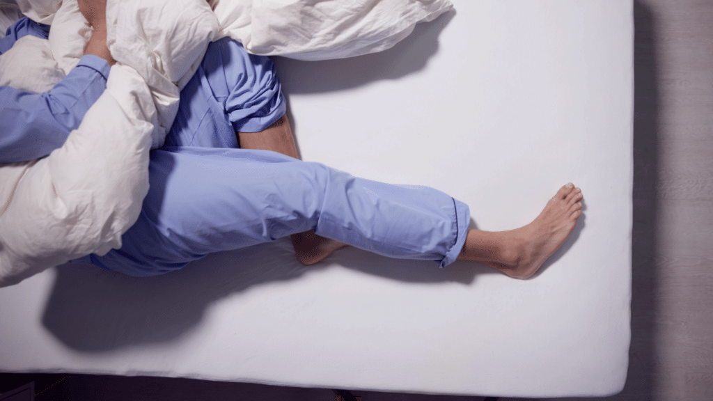 Sleep disruption caused by restless leg syndrome, showing leg tension and nighttime discomfort during rest.