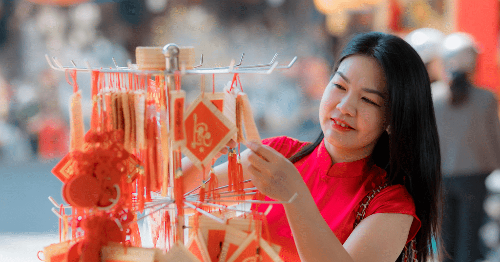 Woman browsing Lunar New Year decorations at a market, selecting red ornaments that symbolize luck, harmony, and fresh energy for the new year