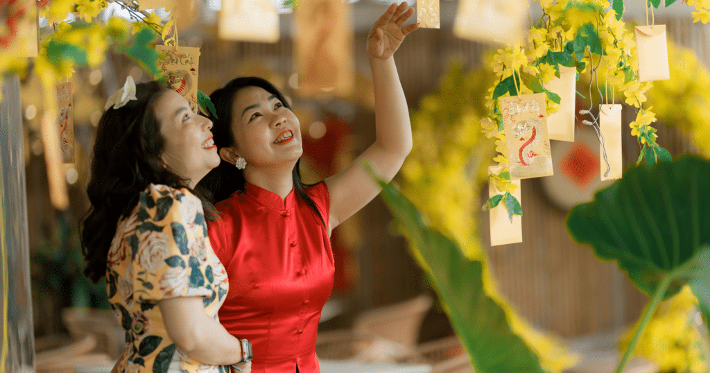 Women enjoying festive Lunar New Year decorations and hanging red envelopes, celebrating renewal, hopes, and blessings for the year ahead