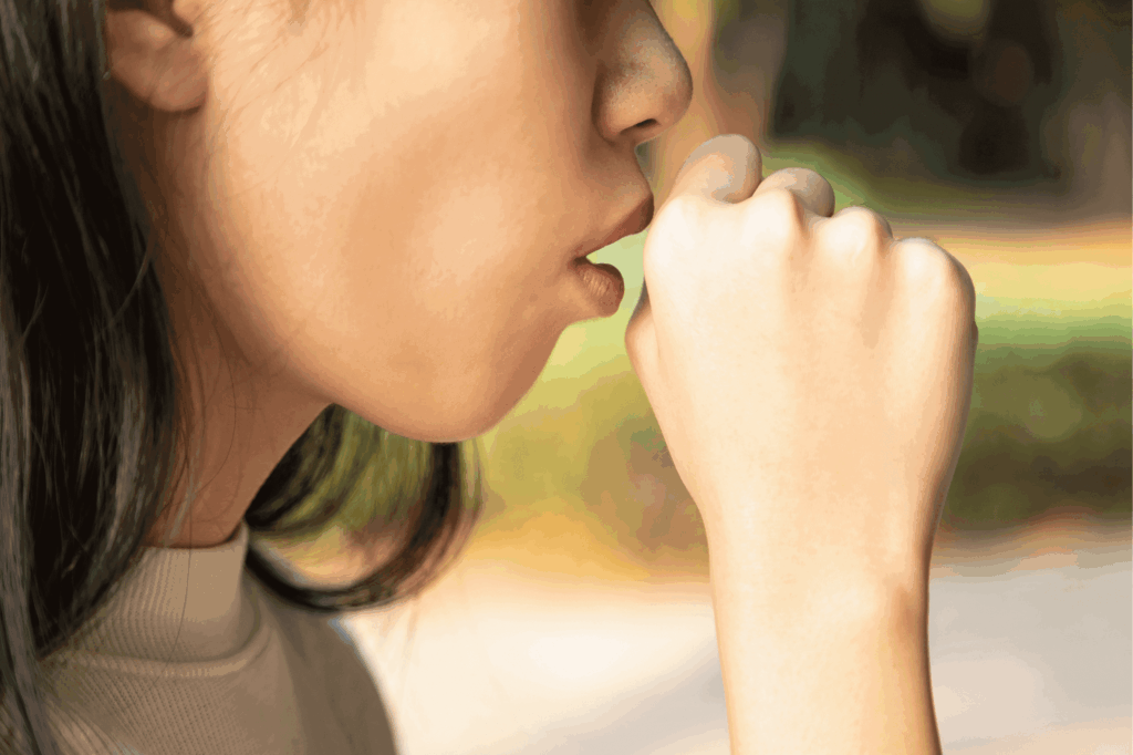Close-up of person coughing into fist outdoors
