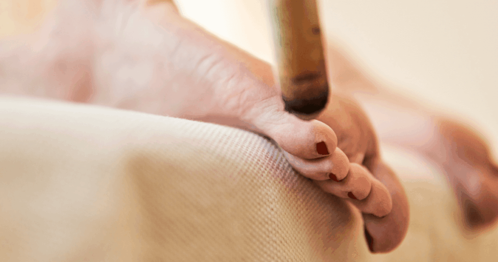 Close view of moxibustion heat applied near pinky toe acupuncture point BL67 demonstrating safe distance and technique sample