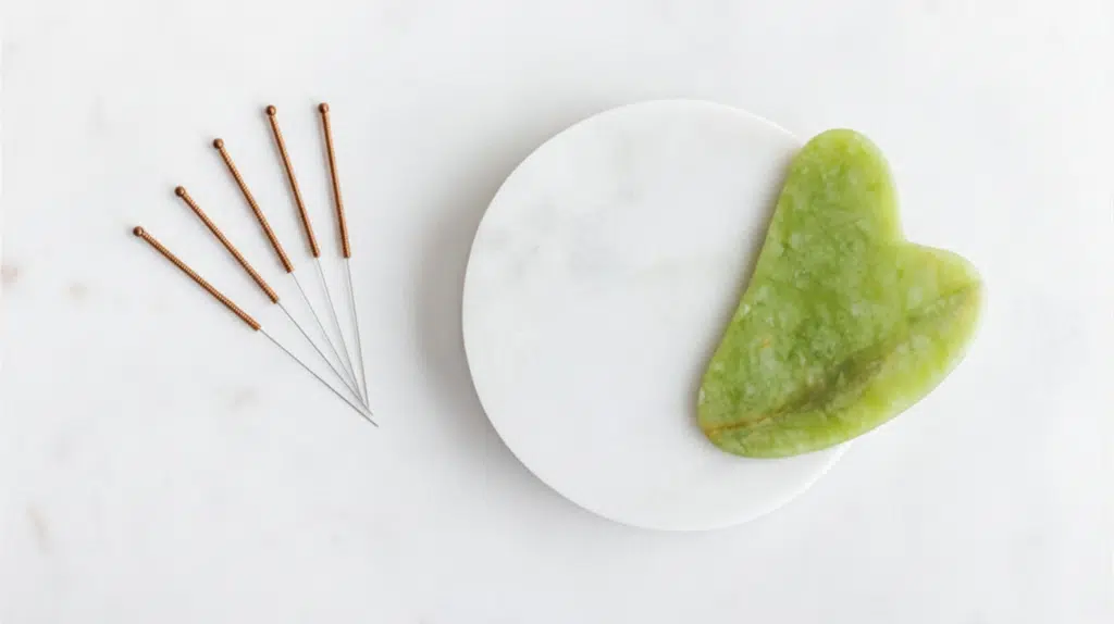 Gua sha tool and acupuncture needles used together for holistic facial treatment