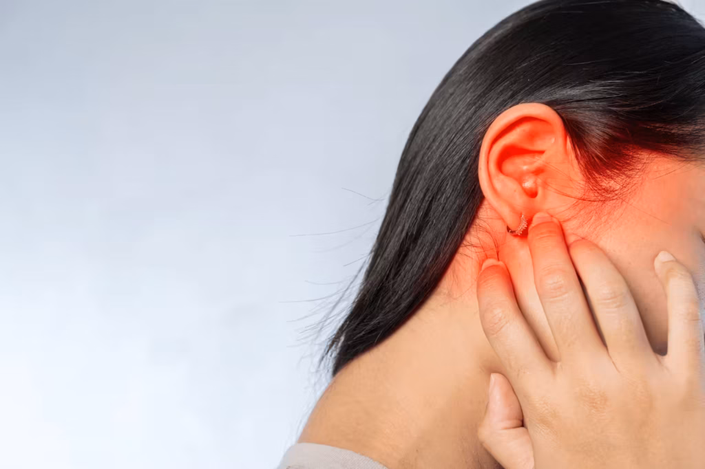 Person touching ear with red highlighted area to show tinnitus discomfort and ringing symptoms