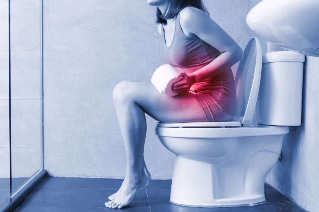 Woman experiencing constipation discomfort while sitting on a bathroom toilet